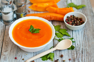 pumpkin-carrot soup-puree in a plate on a wooden background in a rural style. 