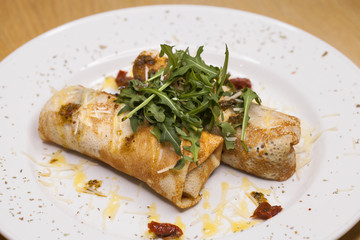 Delicious pancakes with arugula on a white plate