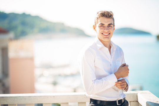 Young handsome man enjoying stay at luxury resort hotel with panoramic view on the sea.Smiling cheerful business man at a earned tropical vacation.Summer vacation traveling.Cruise