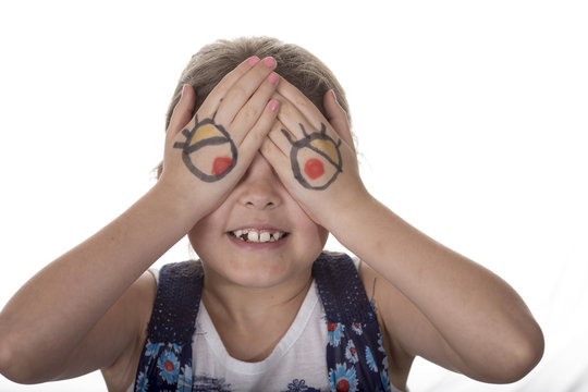 Little girl with cartoon eyes painted on her hands making goofy face.