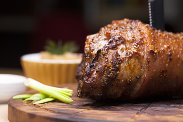 Restaurant dish - large baked pork knuckle on a wooden tray
