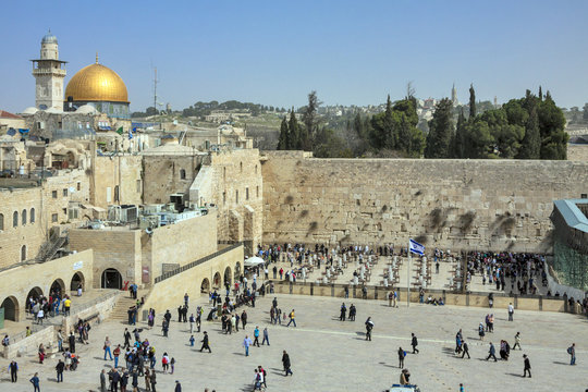 Israel - Jerusalem - Jewish people going and praying at the wailing wall with cupola of Dome of the Rock on background