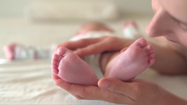 Mommy kissin newborn baby feets, close-up, slow motion video