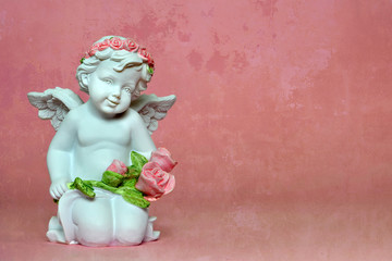 Angel kneeling and holding flowers. Background with copy space.