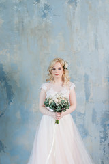 young bride in white dress stands with a bouquet.