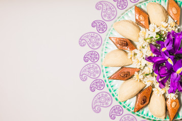 Novruz celebration plate with traditional national pastries in Azerbaijan shekerbura and pakhlava decorated with spring  flowers daffodils and purple fleur de lis silk light grey background copy space
