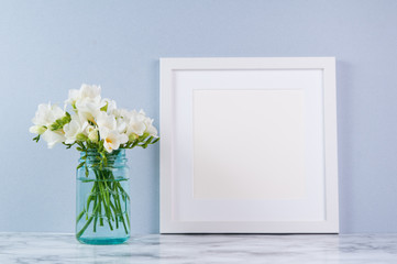 white square frame mock up with white fressia flower bouquet in a blue glass jar