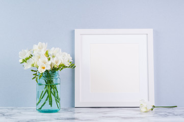 white square frame mock up with white fressia flower bouquet in a blue glass jar