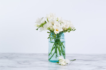 white fressia flowers in a blue jar