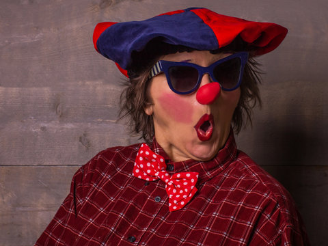 Woman funny clown with red nose and blue sunglasses. Comedy concept.