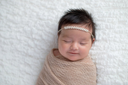 Smiling Baby Girl Wrapped in a Beige Swaddle