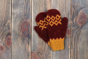 Red and yellow mittens on a wooden background.