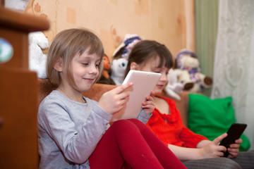 Two sisters playing games on tablets