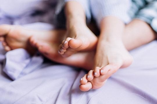 legs of a girl and a guy who lie together on a purple bed