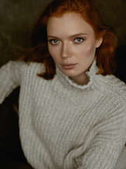 Portrait of a beautiful red-haired girl on a green background in the studio