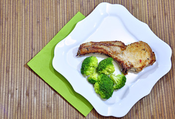 A LARGE PIECE OF STEAK ON THE BONE , OVEN BAKED , SERVED ON WHITE PLATES WITH BROCCOLI