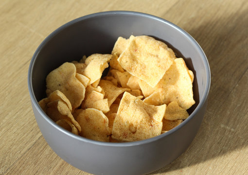  Bowl with Indonesian cassave chips on wooden background