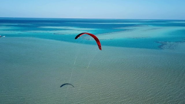 Aerial view young man kite surfing in tropical blue ocean