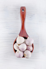 Fresh garlic decorated in a wooden spoon on a white wooden kitchen plate can be used as background
