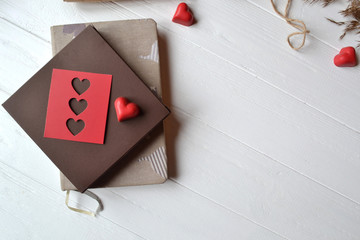Notebook, red hearts, rope and gift box on the white wooden desk. Valentine's Day. Background with place for text.