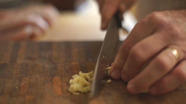 Man cuts garlic on a wooden board side view video
