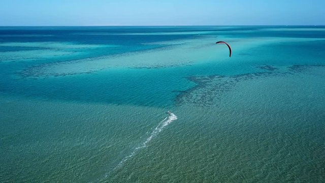 Aerial view young man kite surfing in tropical blue ocean
