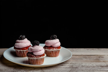 berry cupcakes on a white plate against a dark background. side view