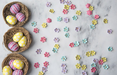 Easter background of little colourful flowers and nests with easter eggs with copy space 