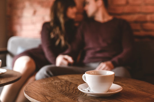 The cup of coffee on the background of the sitting couple