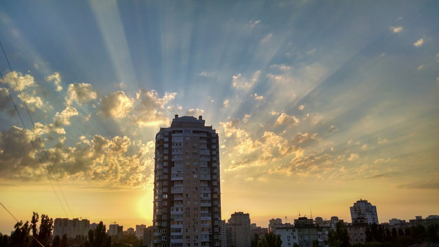 Fototapeta A lonely high-rise residential house against the backdrop of the beautiful sunset sky and the grisly clouds. View from the window from the top. Panorama.