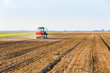 Obraz premium Farmer fertilizing arable land with nitrogen, phosphorus, potassium fertilizer