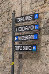 An isolated shot of a direction sign, with a solid stone wall in the background, in Guanajuato, Mexico - 192074501