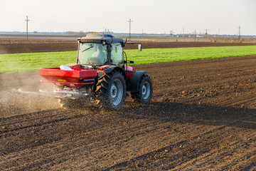 Obraz premium Farmer fertilizing arable land with nitrogen, phosphorus, potassium fertilizer