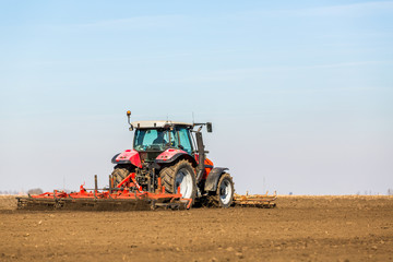 Obraz premium Farmer in tractor preparing land with seedbed cultivator as part of pre seeding activities in early spring season of agricultural works at farmlands.