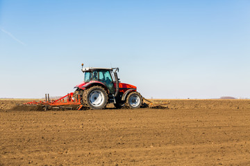 Obraz premium Farmer in tractor preparing land with seedbed cultivator as part of pre seeding activities in early spring season of agricultural works at farmlands.