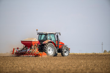 Obraz premium Farmer seeding, sowing crops at field. Sowing is the process of planting seeds in the ground as part of the early spring time agricultural activities.