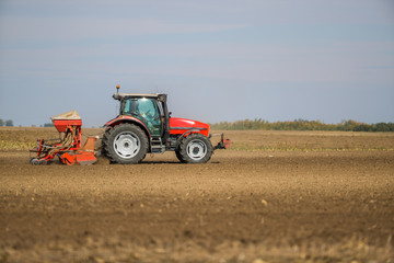 Fototapeta premium Farmer seeding, sowing crops at field. Sowing is the process of planting seeds in the ground as part of the early spring time agricultural activities.