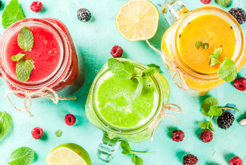 Healthy fresh fruit and veggie smoothies with ingredients on light blue concrete table, copy space 