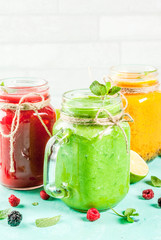 Healthy fresh fruit and veggie smoothies with ingredients on light blue concrete table, copy space 
