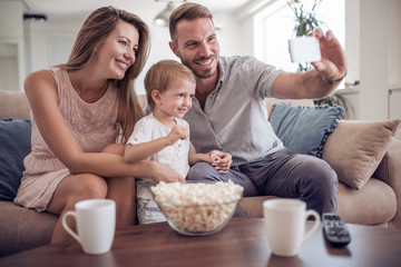 Obraz na płótnie Canvas Happy family on their sofa at home take selfie.