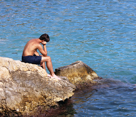 young man sitting in front of the sea, thinking