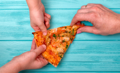 Hands want to take the last piece of pizza  from the table.