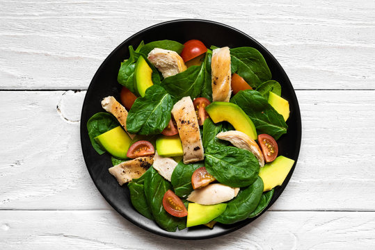 Chicken salad with avocado, spinach and tomatoes cherry in black plate