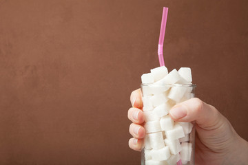 Hand and glass with sugar drink, the concept of excessive consumption of sugar in the diet. Copy space.