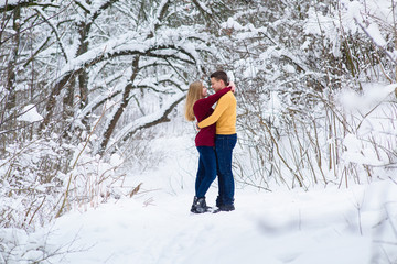 Young couple hugs in winter forest