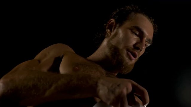 Handsome masculine athlete boxer is wrapping hands with boxing wraps