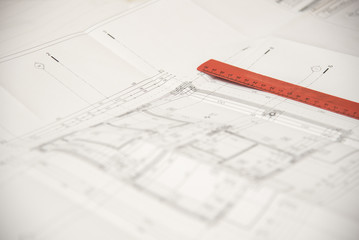 Red ruler on top of a paper blueprint for a certain construction or a building