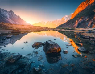 Cercles muraux Himalaya Beautiful landscape with high mountains with illuminated peaks, stones in mountain lake, reflection, blue sky and yellow sunlight in sunrise. Nepal. Amazing scene with Himalayan mountains. Himalayas