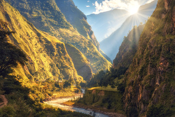 Colorful landscape with high Himalayan mountains, beautiful curving river, green forest, blue sky with clouds and yellow sunlight at sunset in autumn in Nepal. Mountain valley. Travel in Himalayas