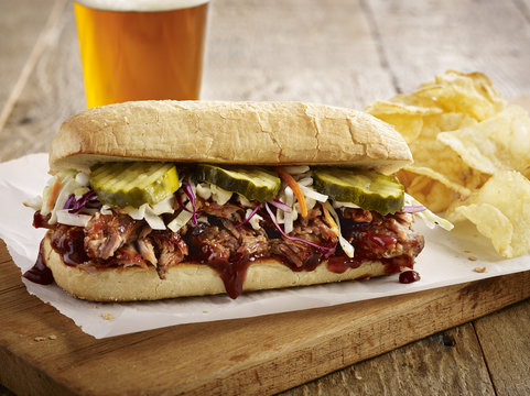 Beer with pulled pork sandwich on cutting board